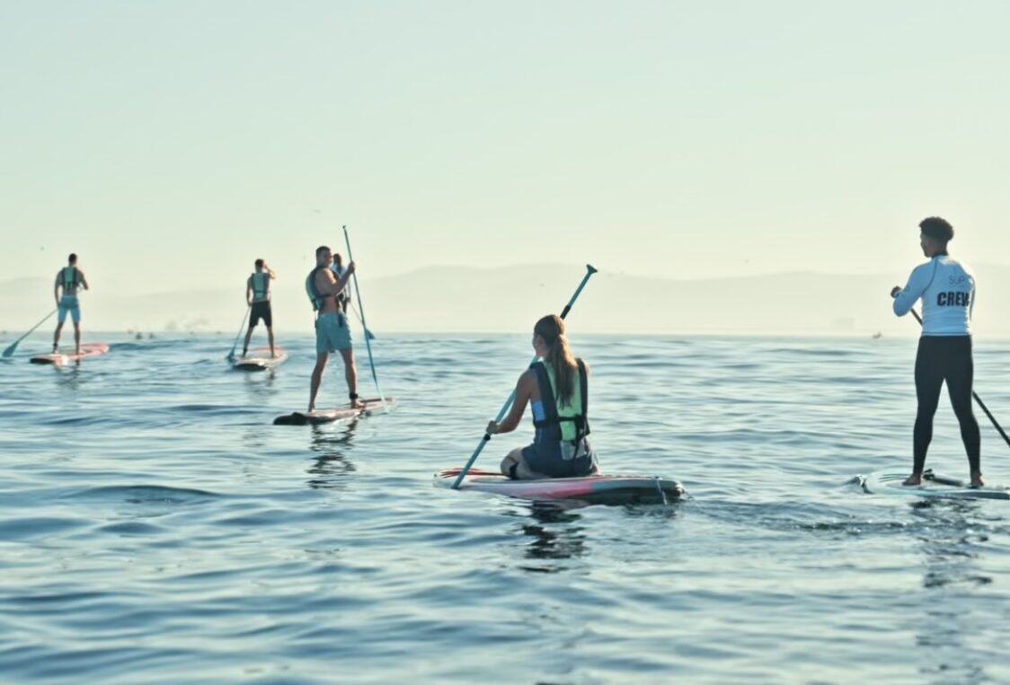 A group of people lead by a SUP Cape town crew member are paddling on the ocean.